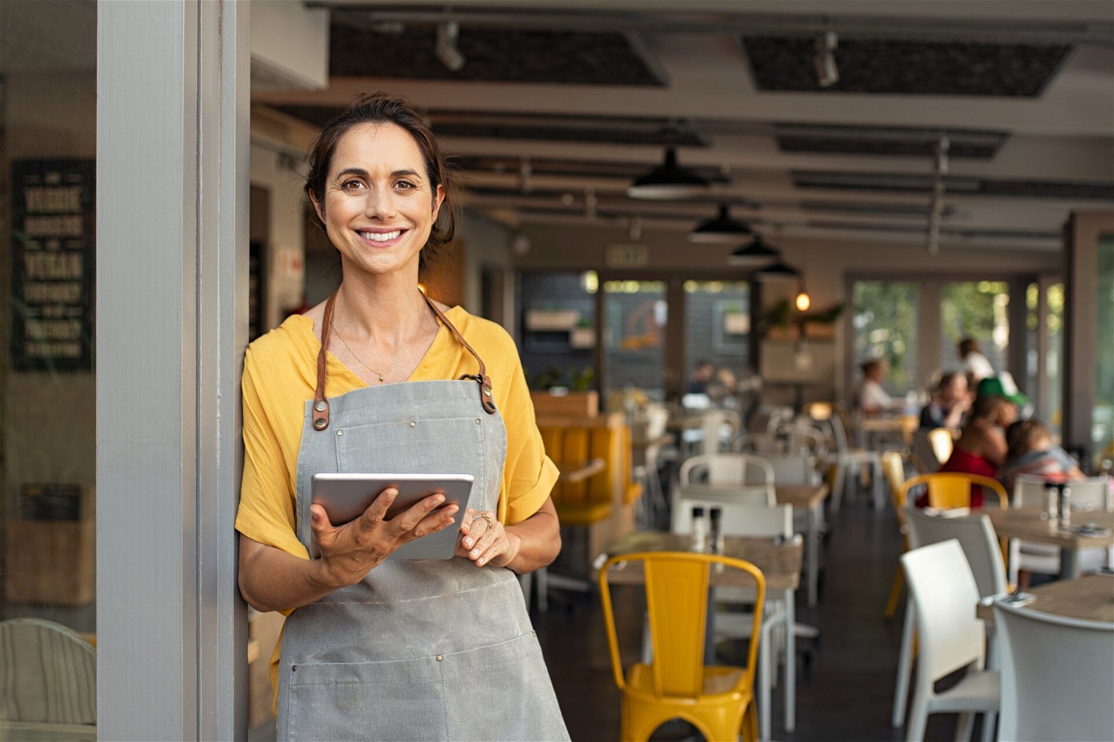 a woman in an apron holding a tablet.