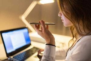 a woman holding a pencil in front of a laptop.